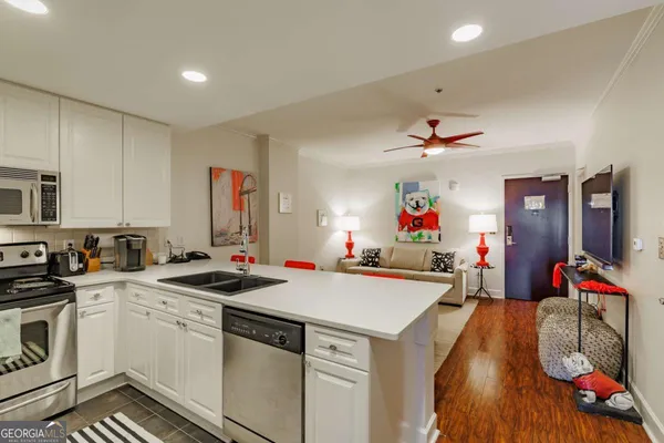 a kitchen with a sink dishwasher a stove and white cabinets with wooden floor