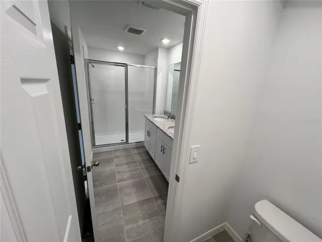 a bathroom with a granite countertop sink a mirror and shower