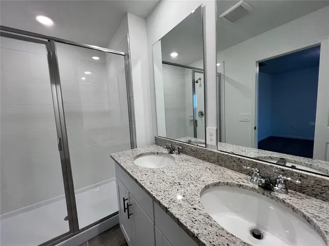 a bathroom with a granite countertop sink mirror and a shower