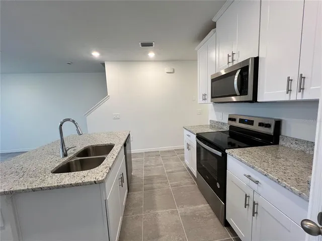 a kitchen with granite countertop a sink and a stove top oven with wooden floors
