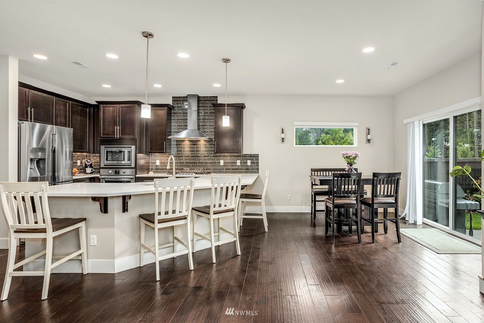 18005 44th Avenue Southeast Bothell, WA 98012 - Photo 9 of 30 a kitchen with stainless steel appliances kitchen island granite countertop a dining table chairs and wooden floor