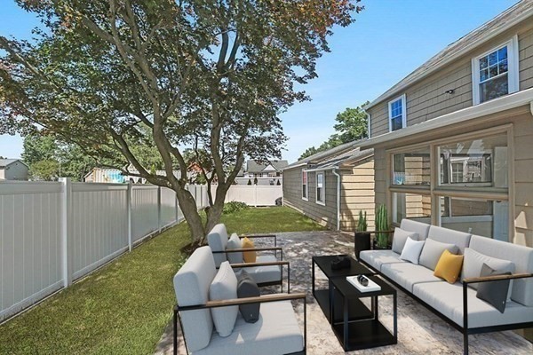 a view of a patio with couches table and chairs and potted plants with large tree