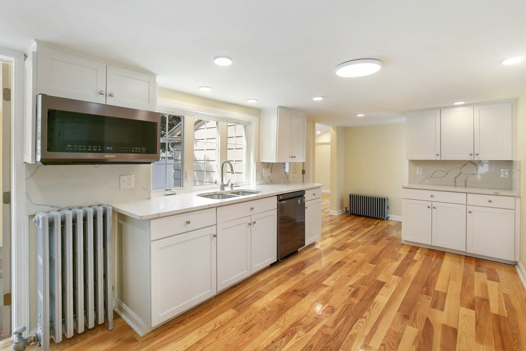 266 Webster Street Worcester, MA 01603 - Photo 15 of 42 a large kitchen with kitchen island granite countertop a stove top oven a sink a window and white cabinets