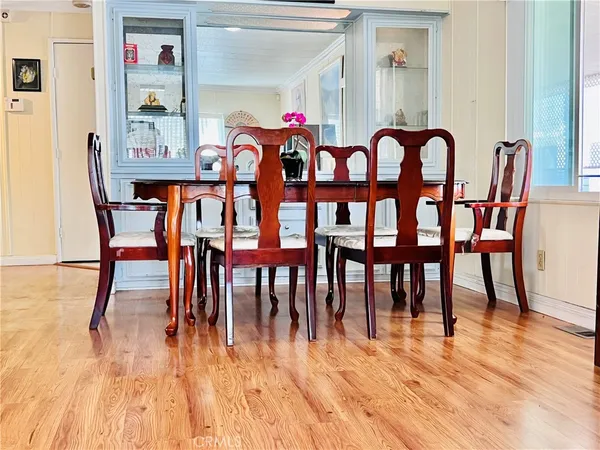 a dining room with furniture floor to ceiling windows and wooden floor