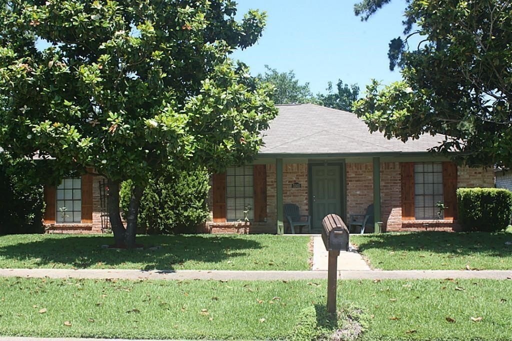 front view of a house with a yard and a large tree