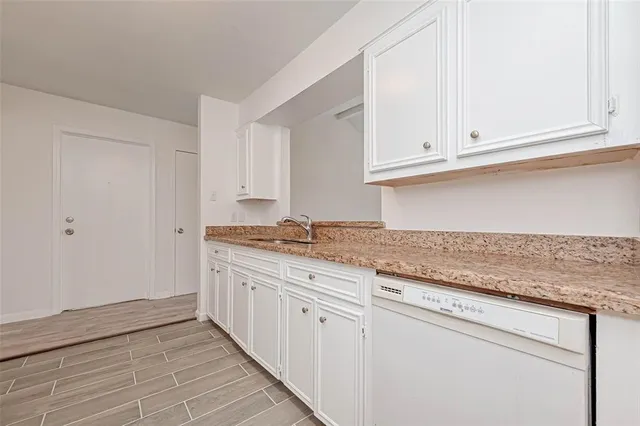 a kitchen with granite countertop white cabinets and a sink