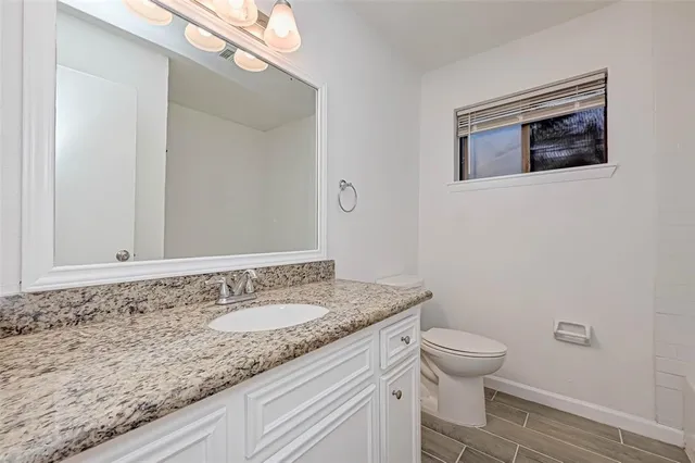 a bathroom with a granite countertop sink a toilet and mirror