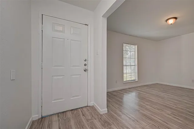 a view of an empty room with wooden floor and a window