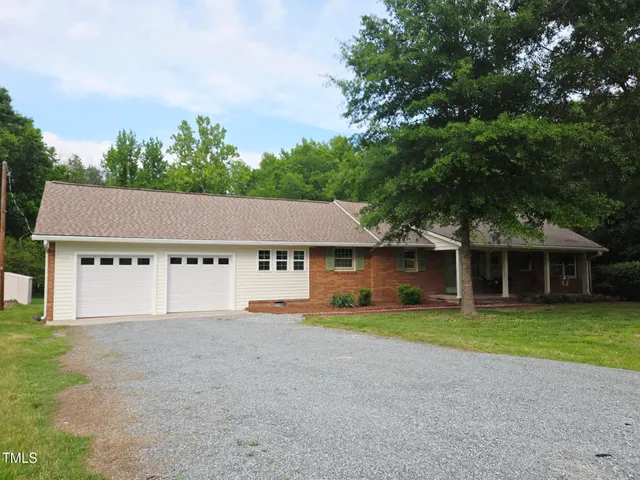 front view of a house with a yard and a large tree