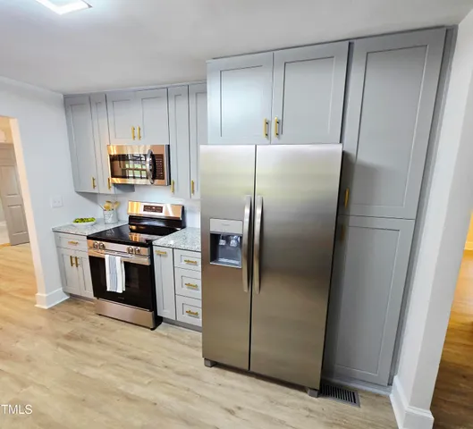 a kitchen with stainless steel appliances granite countertop a refrigerator a stove a sink and a refrigerator with wooden floor