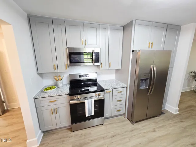 a kitchen with stainless steel appliances a stove a refrigerator a sink a counter space and wooden floor