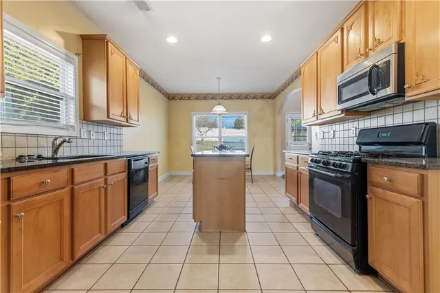 a kitchen with stainless steel appliances granite countertop a stove a sink and a microwave