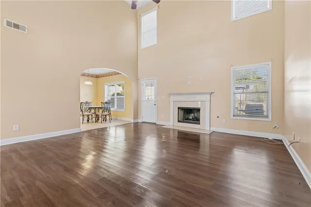 an empty room with wooden floor fireplace and windows