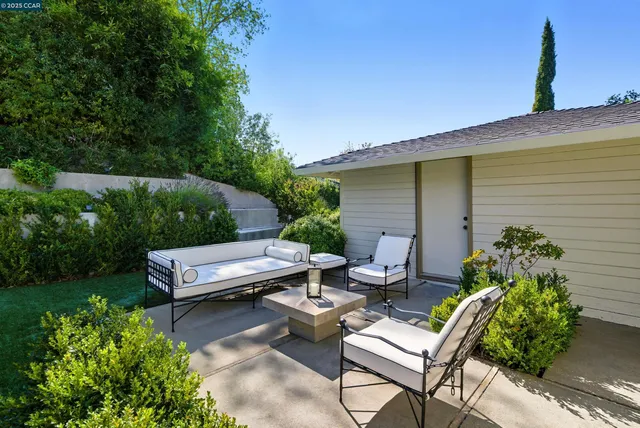 a view of a patio with couches chairs and a table and chairs with wooden fence