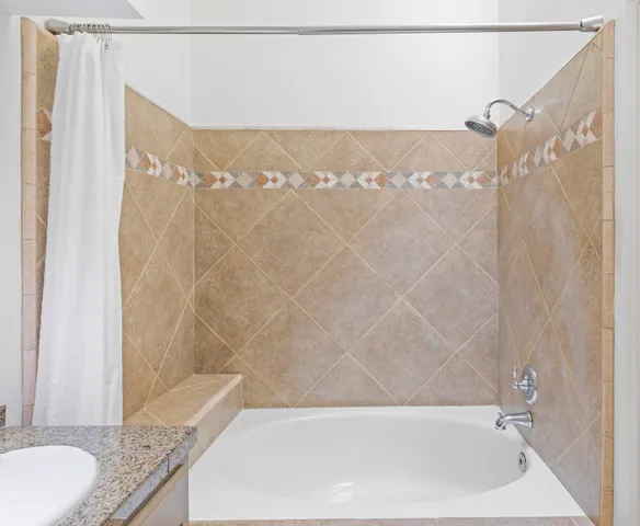 a bathroom with a granite countertop bathtub shower and a sink