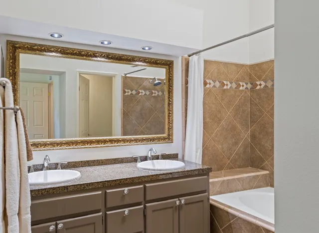 a bathroom with a granite countertop sink mirror and a bathtub