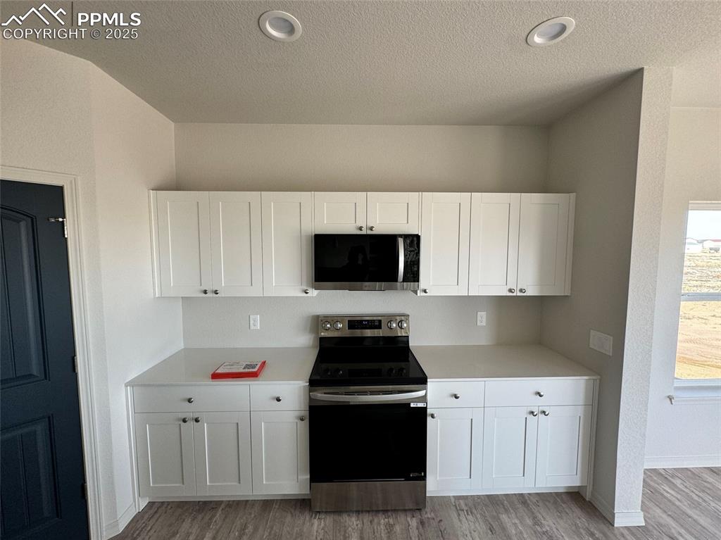 3955 Yoder Road Yoder, CO 80864 - Photo 15 of 27 Kitchen featuring a textured ceiling, light wood-type flooring, stainless steel appliances, and white cabinetry