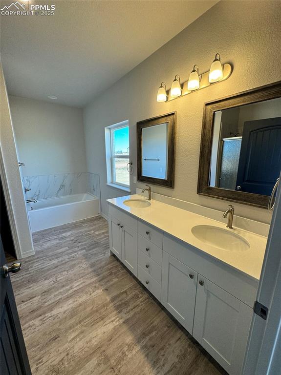 3955 Yoder Road Yoder, CO 80864 - Photo 23 of 27 Bathroom featuring separate shower and tub, hardwood / wood-style floors, vanity, and a textured ceiling