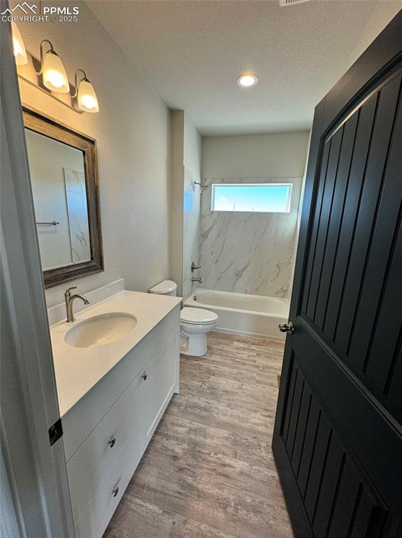 3955 Yoder Road Yoder, CO 80864 - Photo 9 of 27 Full bathroom featuring tiled shower / bath combo, hardwood / wood-style floors, a textured ceiling, toilet, and vanity