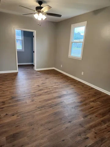 a view of an empty room with wooden floor and a window