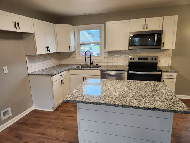 a kitchen with stainless steel appliances granite countertop a stove a sink and a microwave