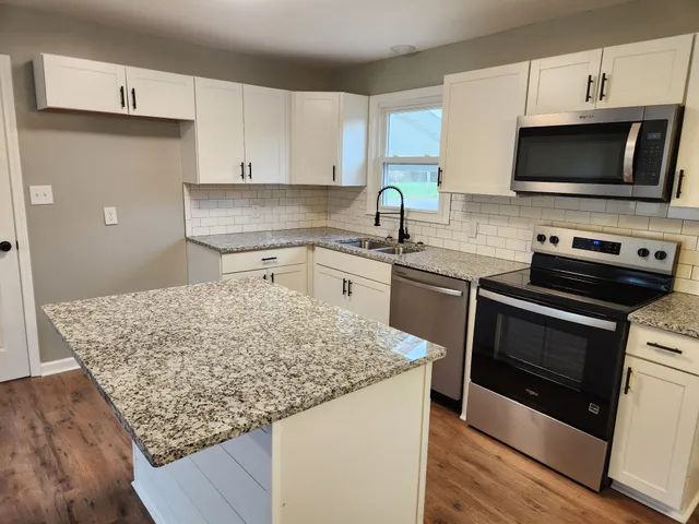 a kitchen with stainless steel appliances granite countertop a sink stove and microwave
