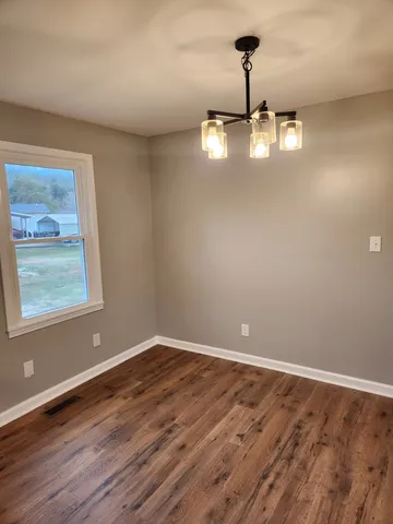a view of empty room with wooden floor and window
