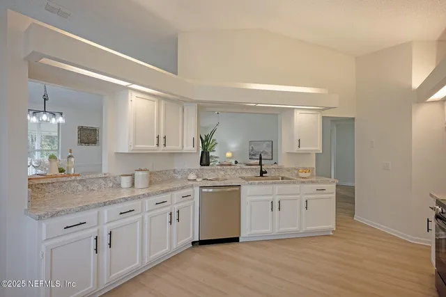 a kitchen with a sink stove cabinets and wooden floor