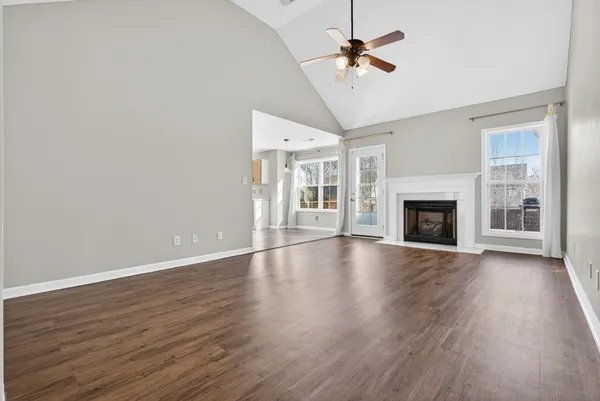 a view of an empty room with wooden floor fireplace and a window