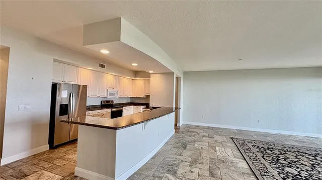 a kitchen with stainless steel appliances granite countertop a refrigerator a sink and a stove