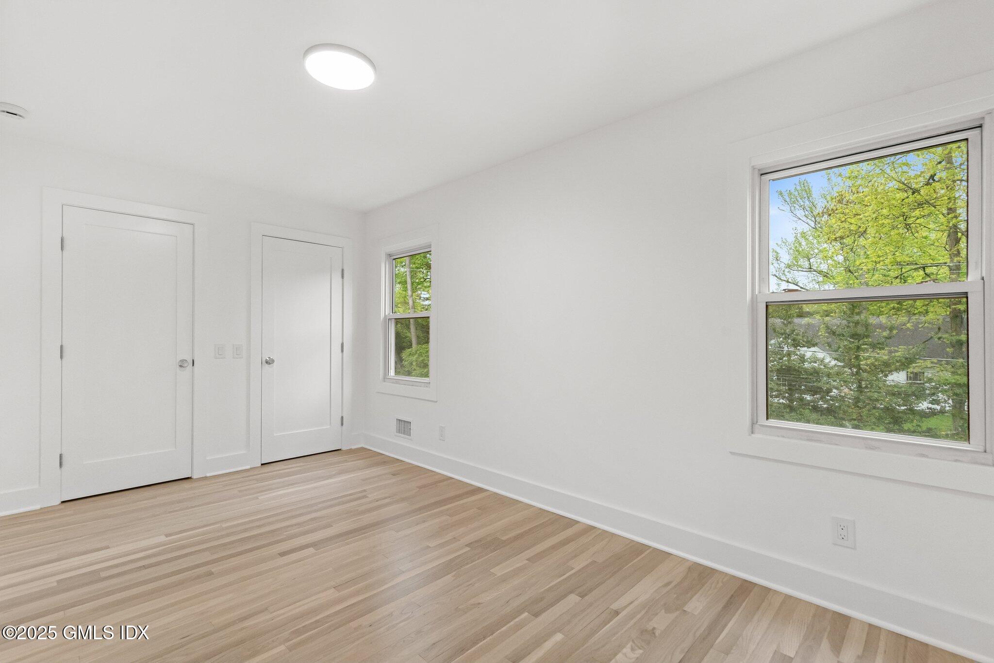 8 Pintail Lane Greenwich, CT 06830 - Photo 21 of 37 an empty room with wooden floor and windows