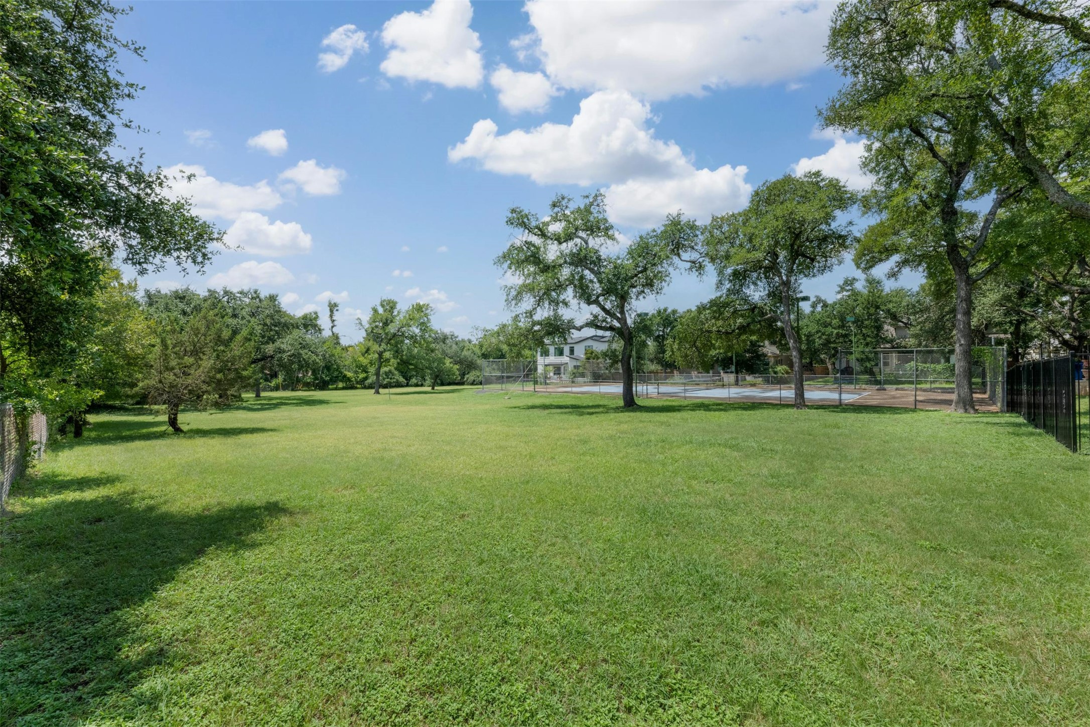 9911 Anderson Mill Road Austin, TX 78750 - Photo 2 of 29 A verdant expanse of lawn provides ample outdoor space, bordering a fenced tennis court for active recreation.