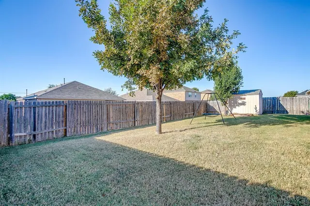 a view of backyard and wooden fence