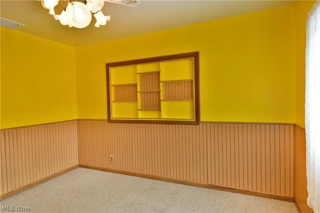 878 Ridge Road Vienna, OH 44473 - Photo 40 of 50 Carpeted spare room featuring a wainscoted wall and a chandelier