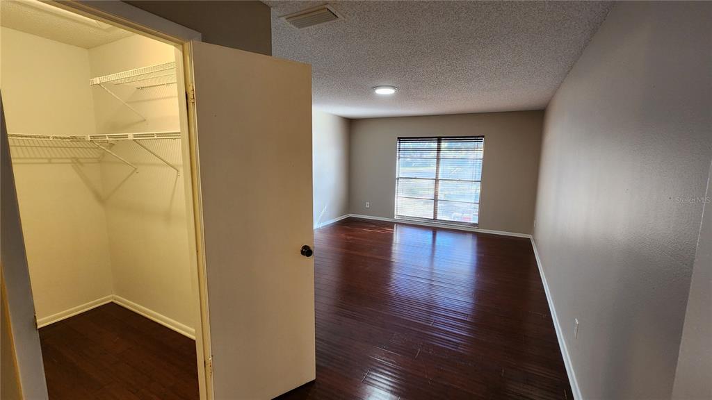 14921 Old Pointe Road Tampa, FL 33613 - Photo 14 of 32 an empty room with wooden floor and windows with curtains