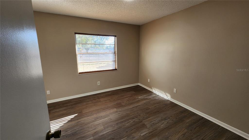 14921 Old Pointe Road Tampa, FL 33613 - Photo 21 of 32 an empty room with wooden floor and windows