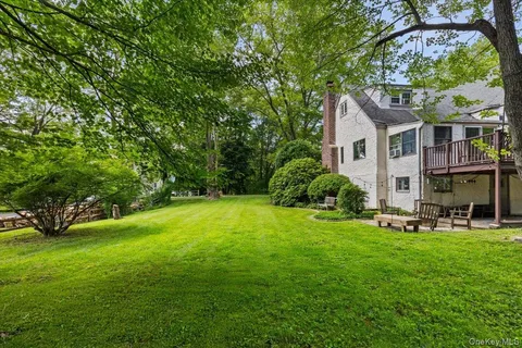 a view of a house with a big yard plants and large trees