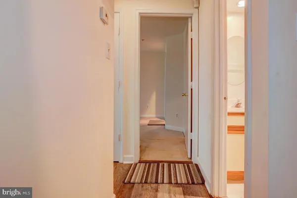 a view of a hallway with wooden floor and a bathroom