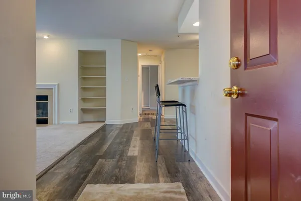 a view of empty room with wooden floor and kitchen