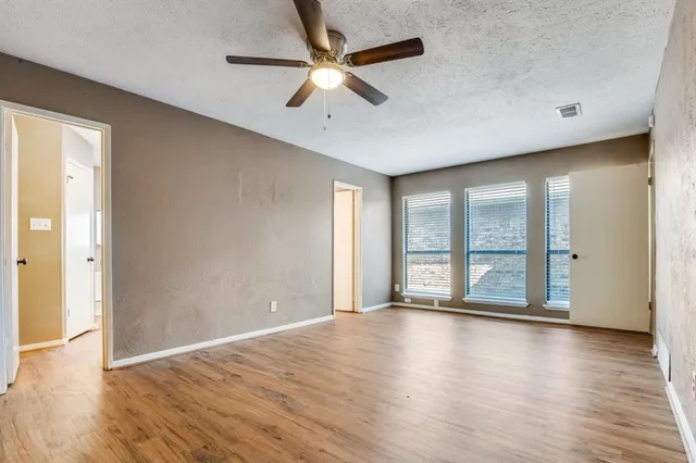 an empty room with wooden floor and windows with curtains