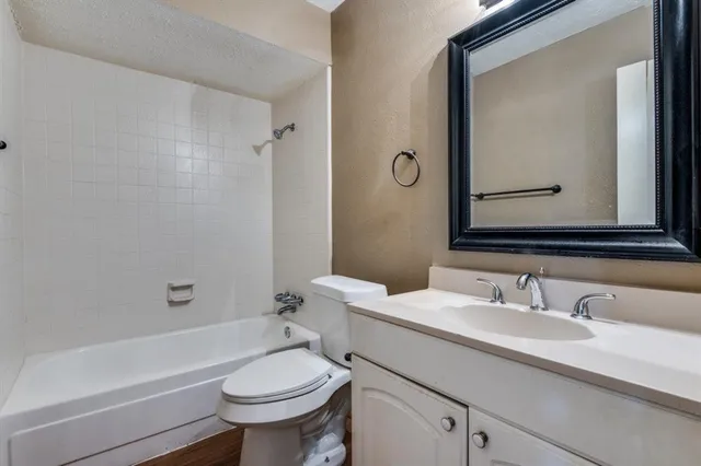 a bathroom with a granite countertop toilet a sink and a bathtub