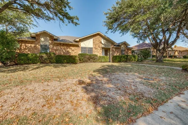 a front view of a house with a yard and large trees
