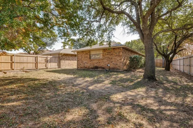 a backyard of a house with large trees and outdoor seating