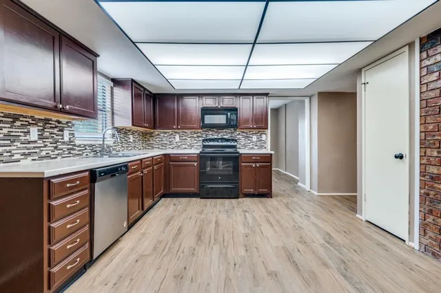 a kitchen with stainless steel appliances granite countertop wooden floors wooden cabinets and sink