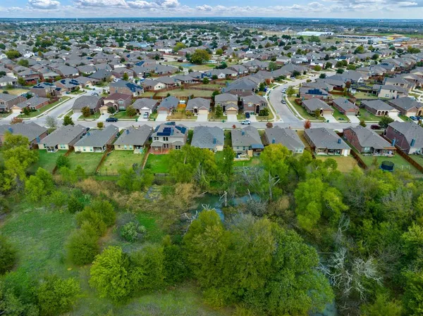 an aerial view of residential houses with outdoor space and trees