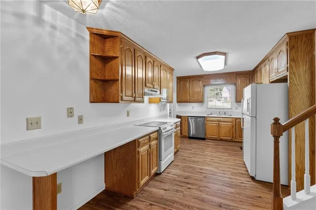 a kitchen with stainless steel appliances a sink cabinets and wooden floor