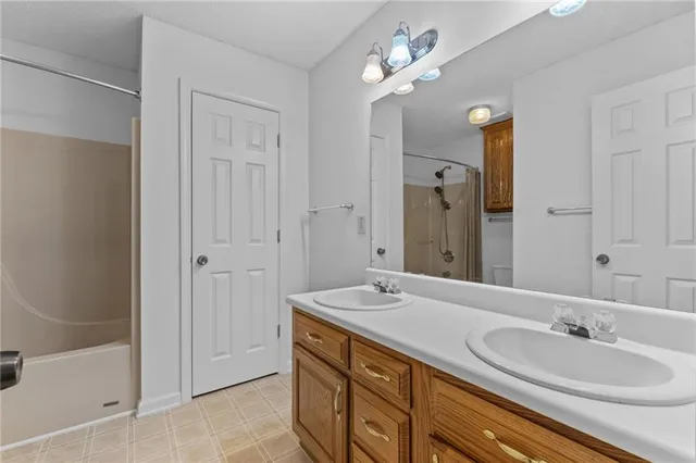 a spacious bathroom with a double vanity sink a large mirror and a bathtub