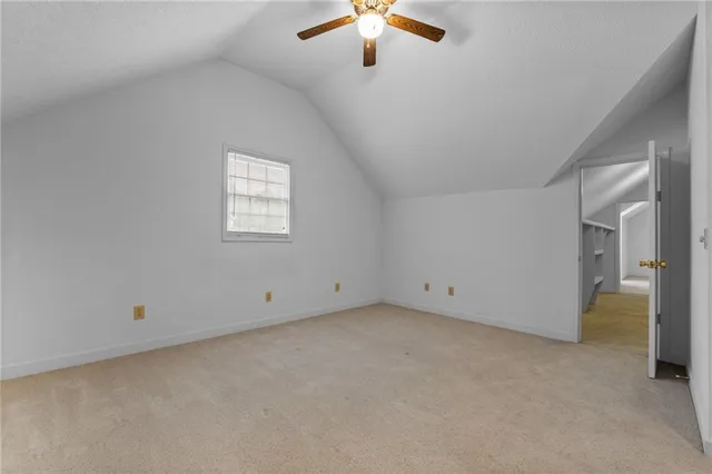 an empty room with chandelier fan and windows