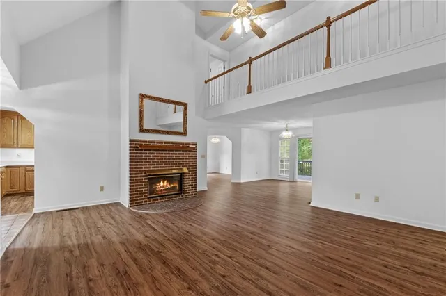 a view of an empty room with wooden floor fireplace and a window