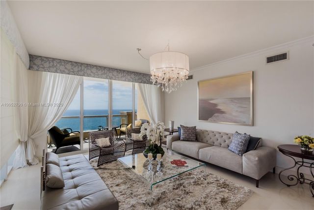 a living room with furniture a large window and a chandelier